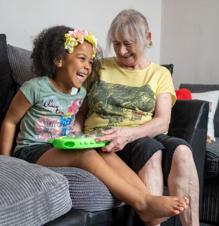 Adult and child playing with a game sat on a sofa