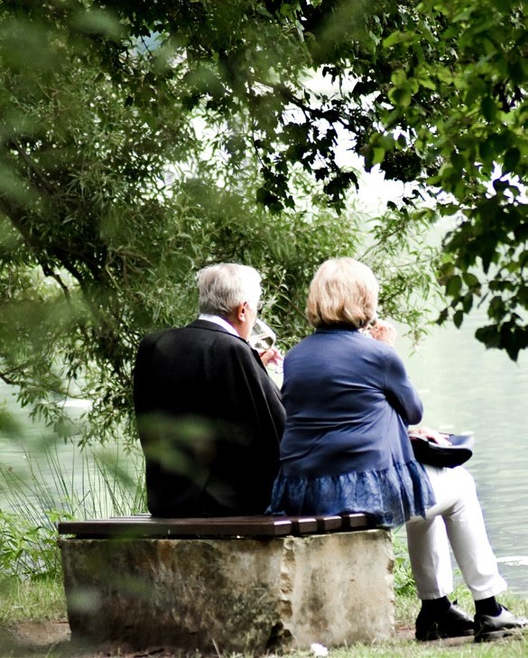 Two people sat on a bench in gillingham looking out over some water