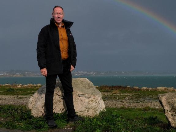 Councillor poses for picture standing in front of rock with sea in background